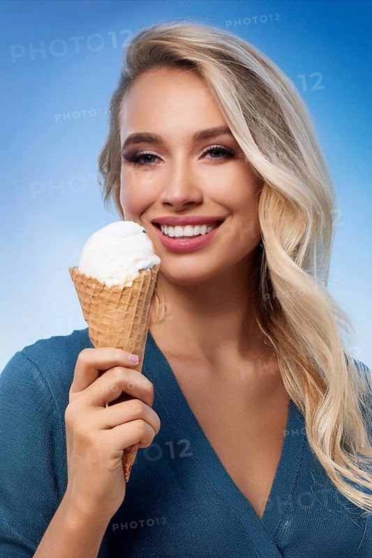 A blonde woman enjoys eating an ice cream in a cone