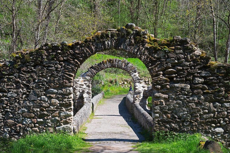 Steinbogenbrücke inmitten der Natur, umgeben von Bäumen und grüner Vegetation, ein ruhiger Wanderweg führt hindurch, Brücke des Teufels, Pont de Diable, romanische Steinbrücke, Fluss Ariège, Montoulieu, Ariege, Frankreich