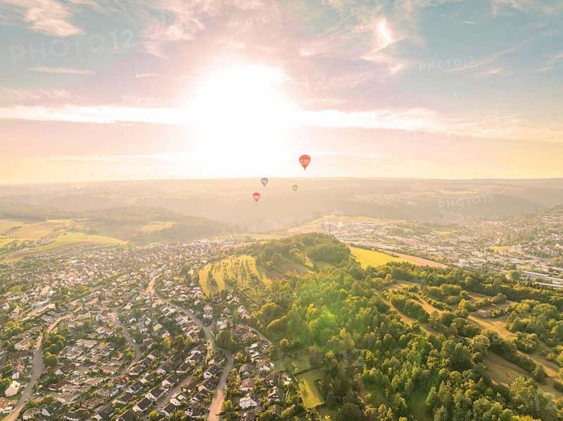 Hot air balloons flying over a town and wooded hills at sunset, Calw, Black Forest, Germany, Europe