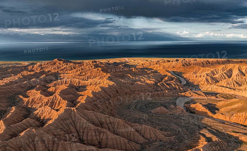 Riverbed runs through a landscape of eroded hills, badlands at sunset, Issyk Kul Lake in the background, aerial view, Canyon of the Forgotten Rivers, Issyk Kul, Kyrgyzstan, Asia