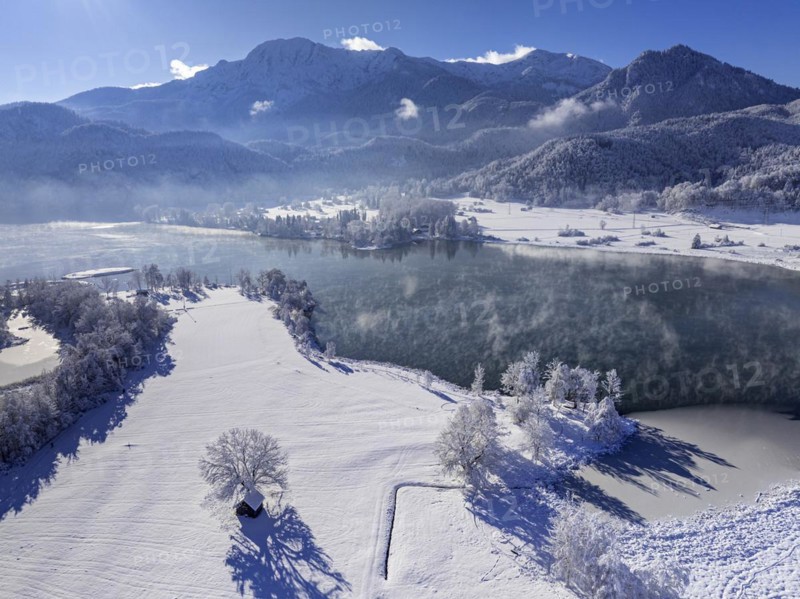Aerial view of a lake in front of mountains in winter, snow, ice, midday light, view of Herzogstand and Heimgarten, Lake Kochel, foothills of the Alps, Bavaria, Germany, Europe