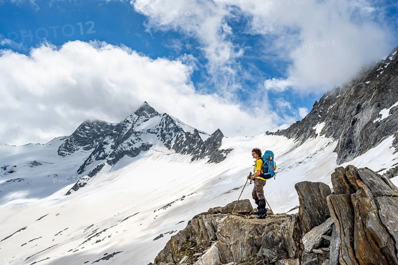 Mountaineer on a rock between snow, descent from the summit of Schönbichler Horn, view of snow-covered and glaciated mountain landscape with summit Großer Möseler, Berliner Höhenweg, Zillertal Alps, Tyrol, Austria, Europe