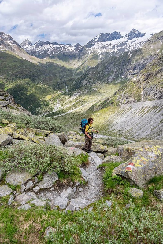 Mountaineer on a hiking trail in front of a picturesque mountain landscape, rocky mountain peaks with snow, valley Zemmgrund with Zemmbach, mountain panorama with summit Großer Mörchner, Berliner Höhenweg, Zillertal Alps, Tyrol, Austria, Europe