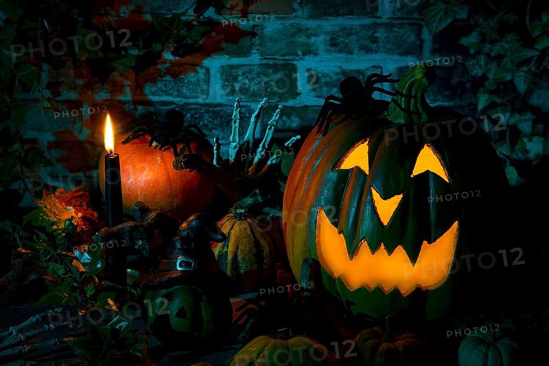Illuminated pumpkin with spiders and candle in a mystical Halloween scene
