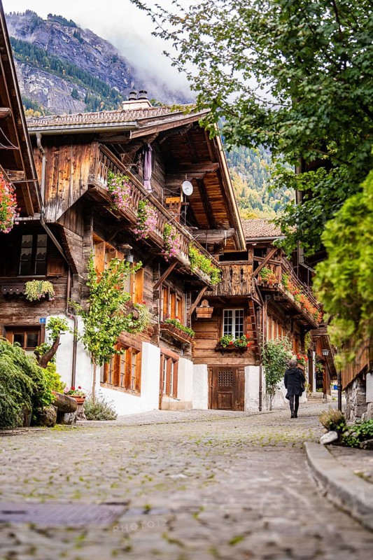 Person walking through a picturesque old street with half-timbered houses in autumn, Lake Brienz, Brienz, Switzerland, Europe