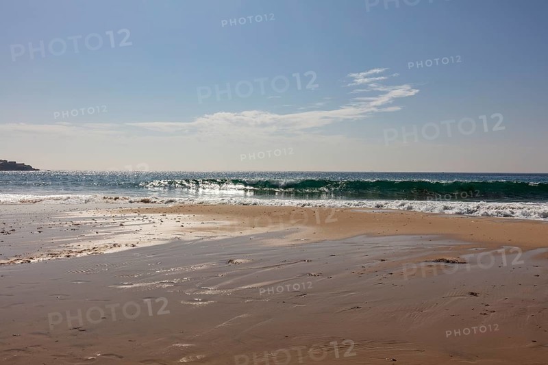 Breaking waves on a calm stretch of beach under a clear sky, Tarifa