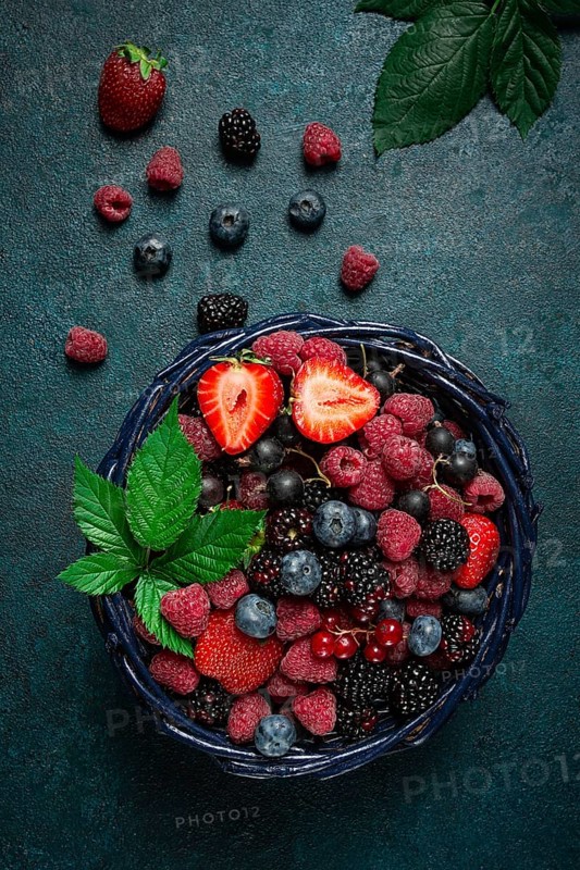 Mix of fresh berries, in a basket, on a wooden gray table, no people, top view