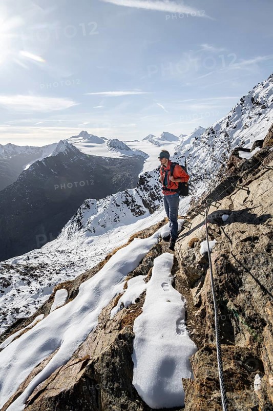 Mountaineer on a secured climb to Ramoljoch with snow in autumn, mountain panorama and glacier, view of Gurgler Ferner with summit Hochwilde and Falschungsspitze, in the morning light, Ötztal Alps, Tyrol, Austria, Europe