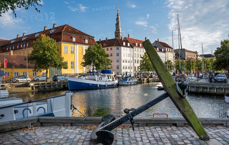 Old anchor, sailing boats, historic buildings and tower of Vor Frelsers Kirke or Church of the Saviour, Christianshavn Canal, Copenhagen, Denmark, Europe
