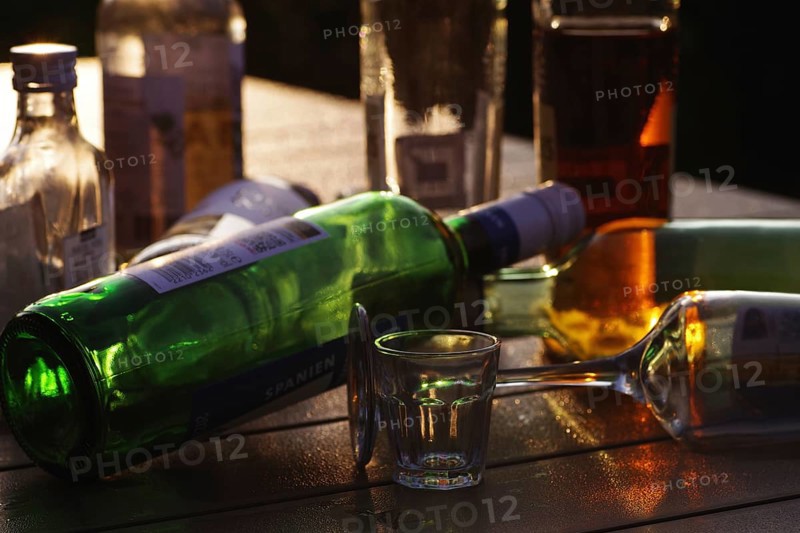Bottles, alcohol, glass, backlight, silhouette, alcohol problem, various bottles standing and lying on a table and glowing in the light of the sun