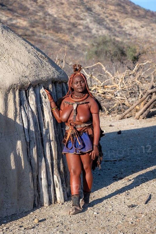 Married Himba woman leaning against a traditional mud house, traditional Himba village, Kaokoveld, Kunene, Namibia, Africa