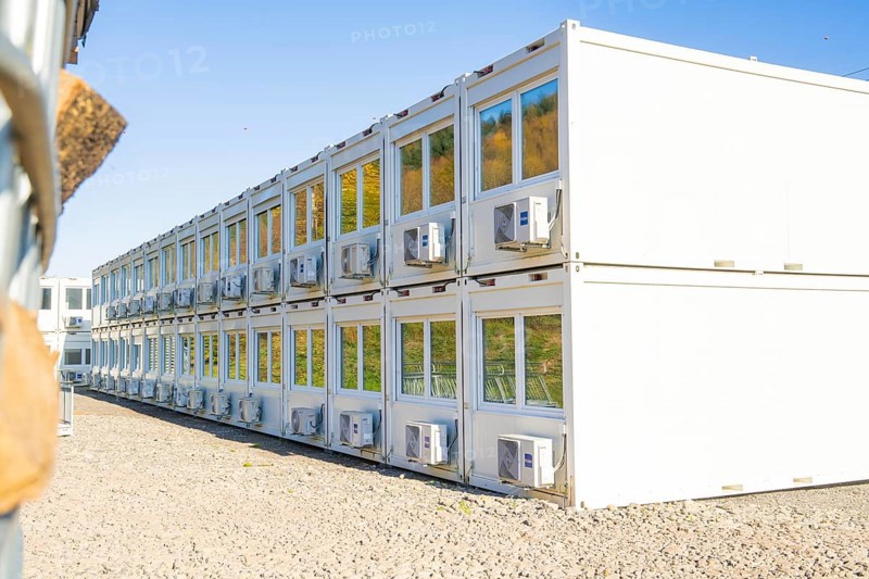 White containers with rows of windows and air conditioning units, reflecting the surroundings, refugee accommodation Beermiß, Calmbach, Black Forest, Germany, Europe