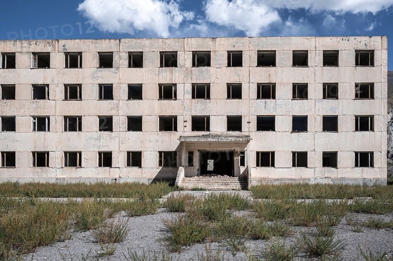Entrance to an abandoned, destroyed residential building, old Soviet apartment blocks in the ghost town, Engilchek, Tian Shan, Kyrgyzstan, Asia