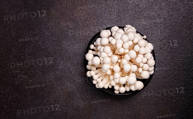 Fresh white shimeji mushrooms, on a black plate, no people.