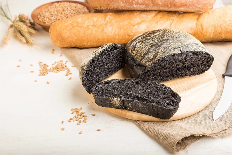 Sliced black bread with different kinds of fresh baked bread on a white wooden background. side view, close up, copy space