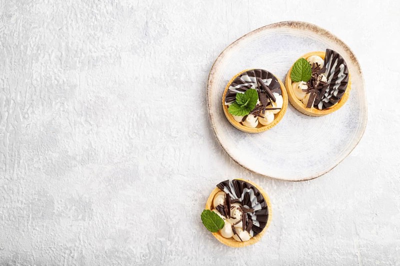 Sweet tartlets with chocolate and cheese cream on a gray concrete background. top view, flat lay, copy space