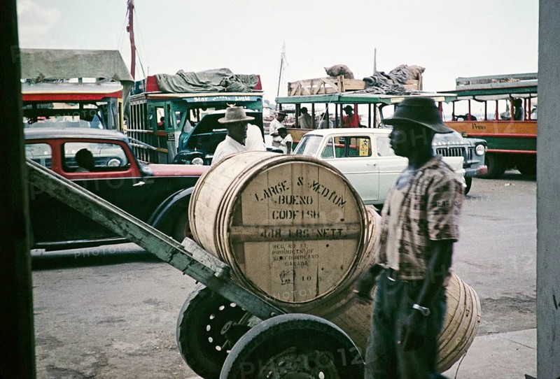 Bues and cars at the harbour, wooden barrels of codfish in foreground, Castries, St Lucia, West Indies 1962