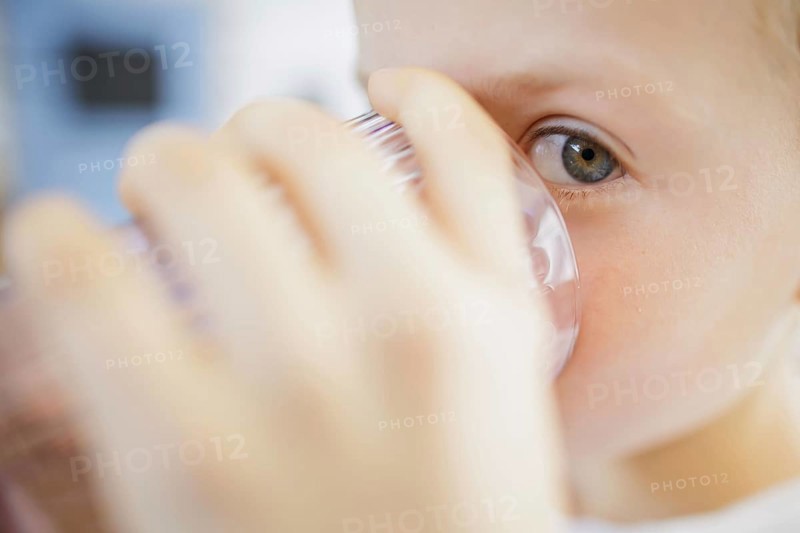 Symbolic photo on the subject of drinking water in high temperatures. A boy drinks a glass of water in hot summer weather. Ziegenrück, 20.07.2024