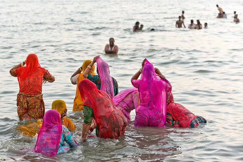 Hindu pilgrims, woman in colourful saris, take a holy dip in the sea in front of sunrise at Ghat Agni Theertham, Rameswaram or Rameshwaram, Pamban Island, Tamil Nadu, India, Asia