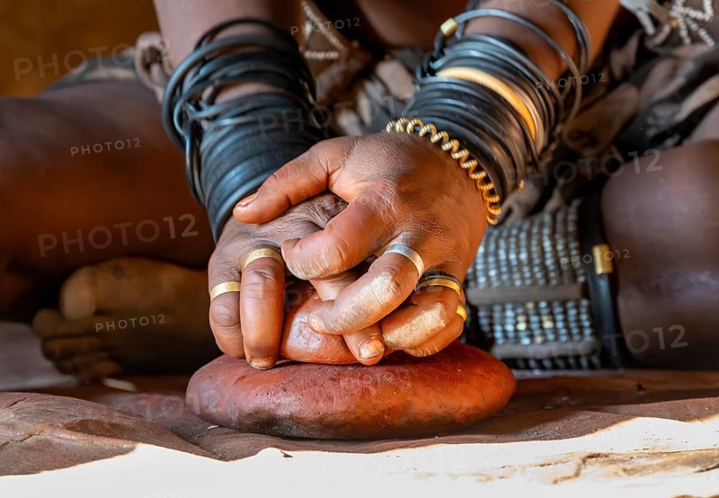 Hands of a woman with painting stone, Traditional Himba woman makes ochre colour for body painting from fat and ochre, near Opuwo, Kaokoveld, Kunene, Namibia, Africa