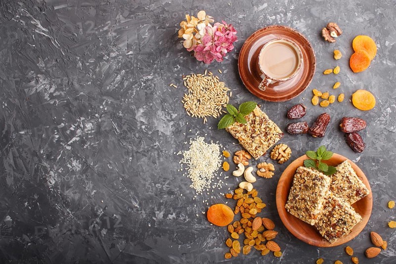 Homemade granola from oat flakes, dates, dried apricots, raisins, nuts with a cup of coffee on a black concrete background. Top view, flat lay, copy space