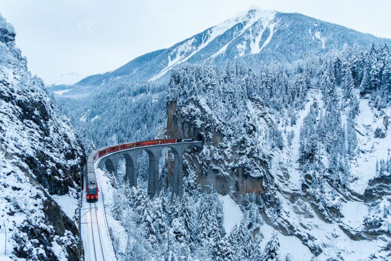 Rhaetian Railway train at the famous Landwasser Viaduct on the Albula railway Stadler Rail passenger train in the Alps in Filisur, Switzerland, Europe