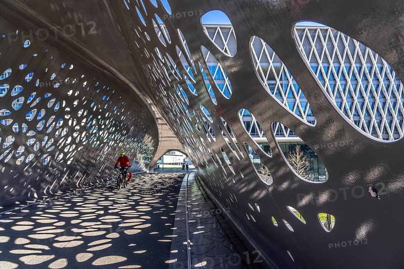 Light effects from the sun in the Parkbruk, a cycle and pedestrian bridge in the city centre of Antwerp, spanning a multi-lane city centre road with tram lines, and thus connecting two lively city districts Kop Spoor Noord and Eilandje, Belgium, without any crossings, Europe