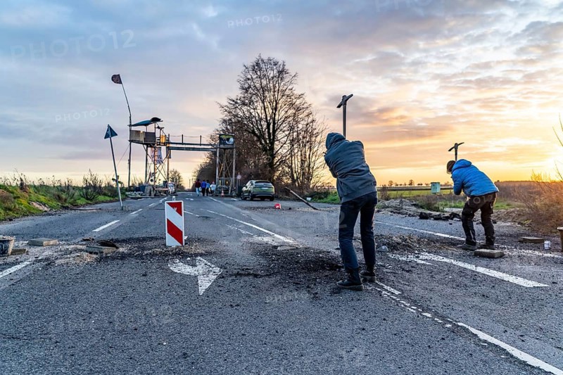Climate activists chop up the asphalt of a road to erect obstacles, barricades, to prevent the police from evicting the occupied hamlet of Lützerath, the remains of the village are to make way for lignite mining, an eviction is imminent, North Rhine-Westphalia, Germany, Europe