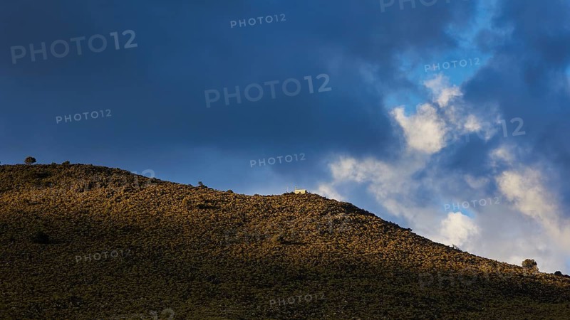 Sunlight and shadow play across a grassy hill under a dramatic sky with dense clouds, Lefka Ori, White Mountains, mountain massif, west, Crete, Greece, Europe