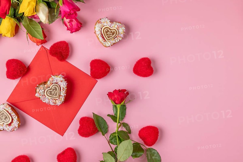 Valentine's Day composition with roses, hearts and envelope, heart-shaped cupcakes, on a pink background