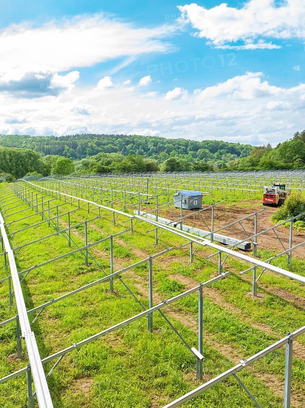 Metal frames of a solar park under construction in a rural area, surrounded by forests and under a blue sky with scattered clouds, construction of the Black Forest Nature solar park, Weil der Stadt, Germany, Europe