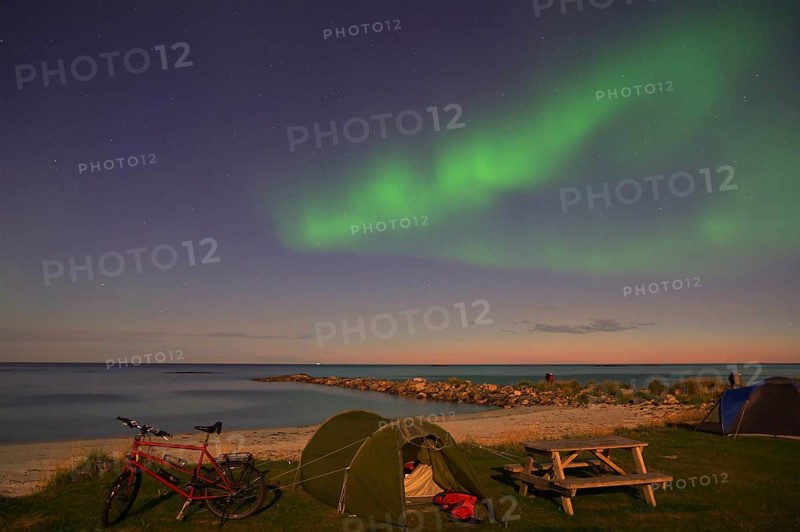 Green northern lights and stars in the sky above a beach with tent and bicycle at night, Bleik, Vesteralen, Langoya, Nordland, Norway, Europe