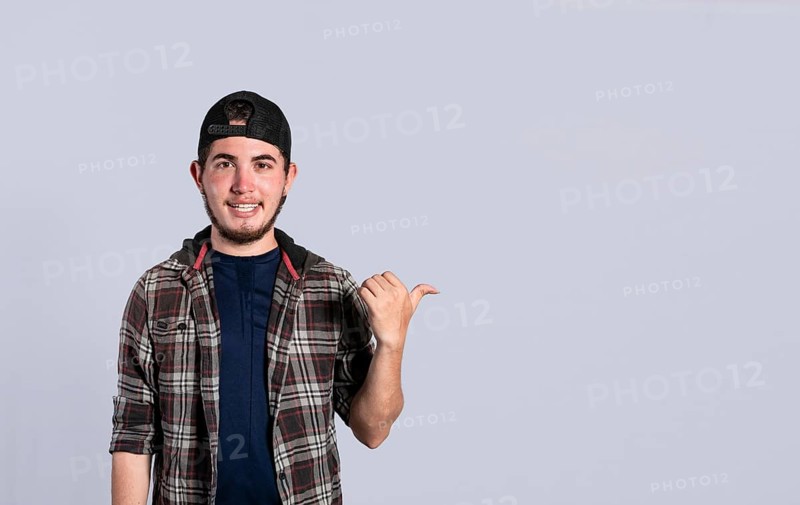 Cheerful bearded man with a friendly smile shows you the direction to a nice place, a friendly guy pointing his thumb to his right