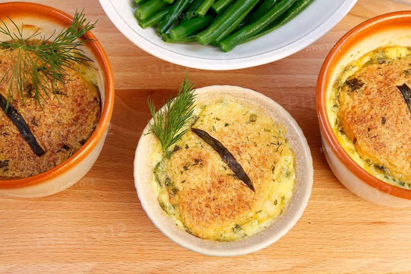 Swabian cuisine, oven-baked pike-perch with princess beans and lemon sauce, fish dish, pike-perch fillet, green beans, dill, starter, from the oven, ramekins, soufflé moulds, served on a wooden board, traditional cuisine reinterpreted, food photography, studio, Germany, Europe