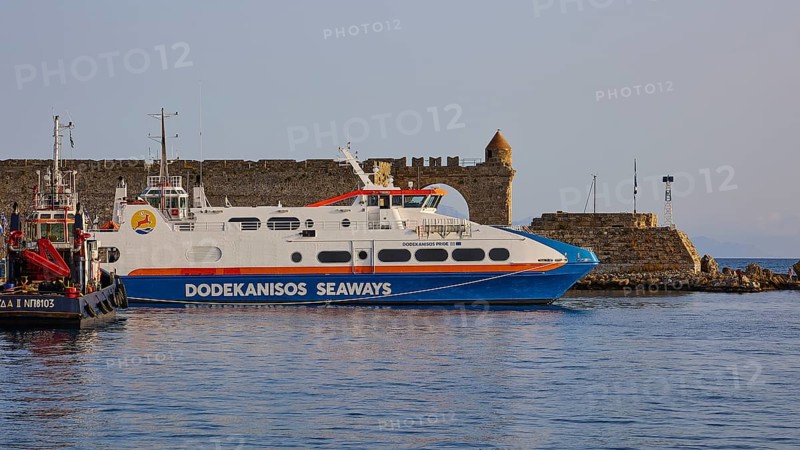 A white ferry lies in front of an old coastal fortification in the calm sea, De Naillac Tower, harbour area, Rhodes Town, Rhodes, Dodecanese, Greek Islands, Greece, Europe