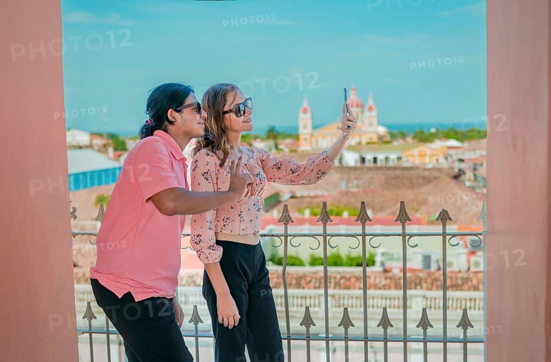 Tourist couple taking a selfie at the viewpoint of the La Merced church. Happy tourists taking self portrait at the viewpoint of the La Merced church, Granada
