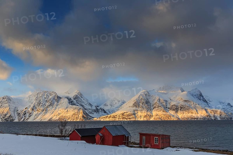 Red boathouses, coast, snowy mountains, fjord, morning light, clouds, snow, Lyngen Alps, Norway, Europe
