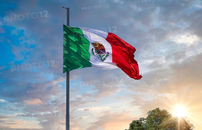 Los Cabos, Mexico, Mexican tricolor national striped flag proudly waving at mast in the air with Aztec symbol for Tenochtitlan, Central America
