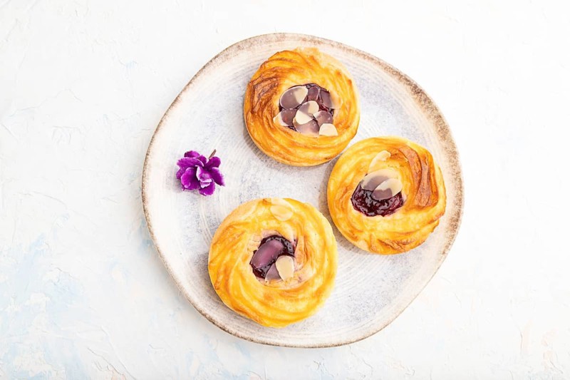 Small cheesecakes with jam and almonds with cup of coffee on a white concrete background. top view, flat lay, close up