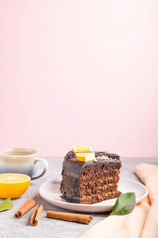 Homemade chocolate cake with orange and cinnamon with cup of coffee on a gray and pink background with orange textile. side view, selective focus, copy space