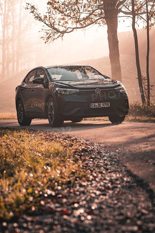 A Volkswagen stands on an autumn road in the light of the setting sun and surrounded by trees, electric car VW ID5, Deer Carsharing, Gechingen, Black Forest, Germany, Europe