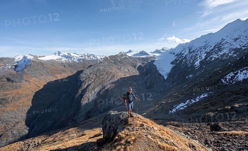 Mountaineer standing on a rock, surrounded by an impressive mountain landscape with snow-covered peaks in autumn View of Gurgler Ferner with summit Hochwilde and Falschungsspitze, Ötztal Alps, Tyrol, Austria, Europe