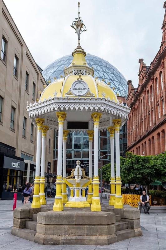 Yellow historic pavilion in a public square surrounded by old buildings, Belfast