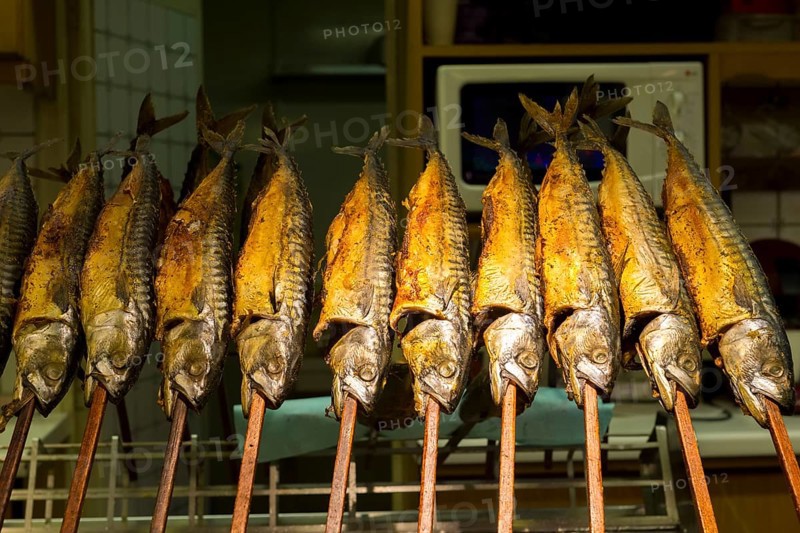 Grilled mackerel on sticks at a stand with golden colour and traditional atmosphere, Kitchen, Cannstadter Volksfest, Stuttgart, Baden-Württemberg