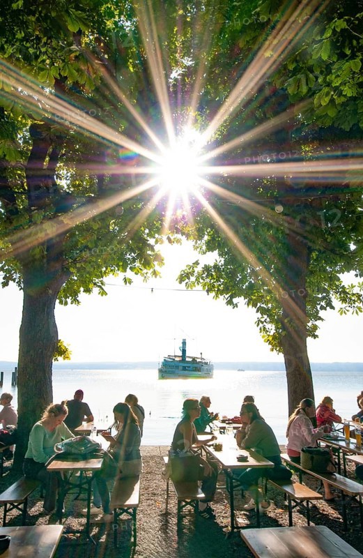 People in a beer garden under chestnut trees in Herrsching am Lake Ammer, in the background a steamer on the Lake Ammer, Bavaria, Germany, Europe