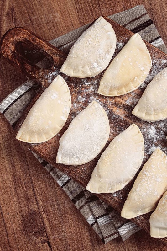Traditional Polish dish, dumplings, raw, frozen, on a cutting board, wooden table, top view, no people