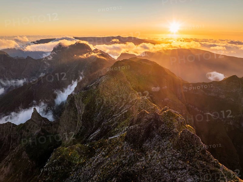 Aerial drone view of mountains over clouds near Pico Ruivo on sunset. Madeira island, Portugal, Europe