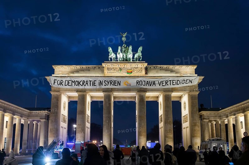 A banner For Democracy in Syria / Defend Rojava hangs at the Brandenburg Tor, Berlin, 16 December 2024