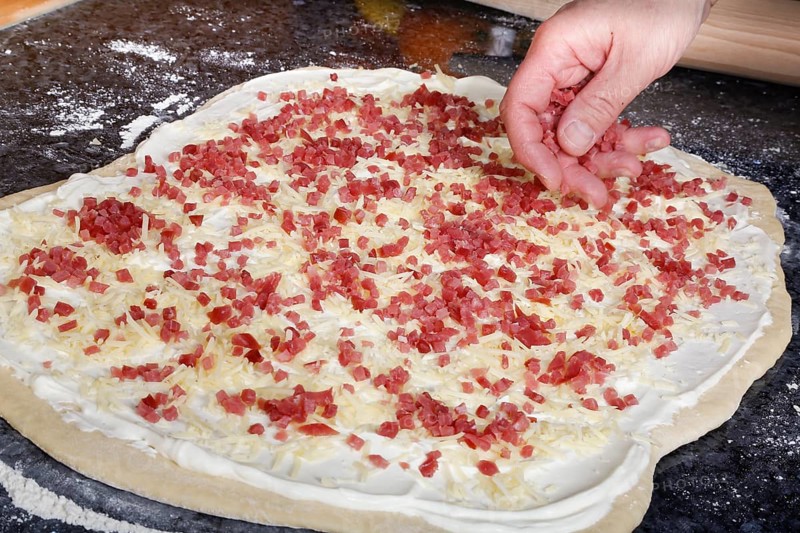 Swabian cuisine, preparation of savoury yeast plait with smoked meat, salty wreath bread, yeast yeast dough pastries, raw yeast dough sprinkled with diced bacon, grated cheese, sour cream, grandmother's cooking, regional, home cooking, typical Swabian cuisine reinterpreted, traditional cuisine reinterpreted, men's hands, food photography, studio, Germany, Europe