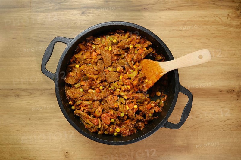 Overhead view of beef and vegetables ragout on wooden countertop in the kitchen